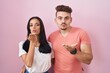 © Krakenimages.com - Young hispanic couple standing over pink background looking at the camera blowing a kiss with hand on air being lovely and sexy. love expression.
