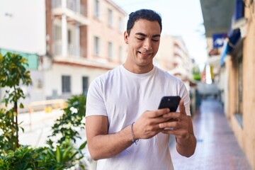 Sticker - Young hispanic man smiling confident using smartphone at street