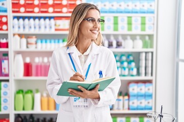 Poster - Young blonde woman pharmacist writing on document at pharmacy