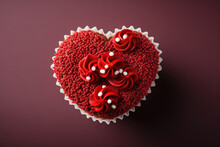 A Heart Shaped Red Velvet Cupcake Against A Burgundy Red Fading Background