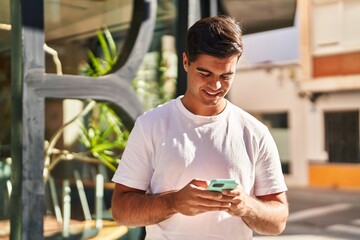 Sticker - Young hispanic man smiling confident using smartphone at street