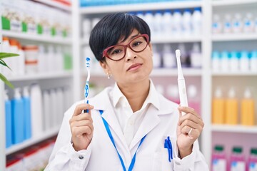 Canvas Print - Young asian woman with short hair doing toothbrush comparative at pharmacy relaxed with serious expression on face. simple and natural looking at the camera.