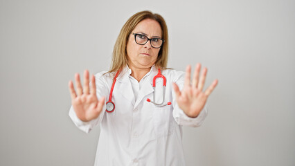 Wall Mural - Middle age hispanic woman doctor standing with serious expression doing calm gesture over isolated white background