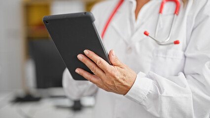 Wall Mural - Middle age hispanic woman doctor using touchpad at the clinic