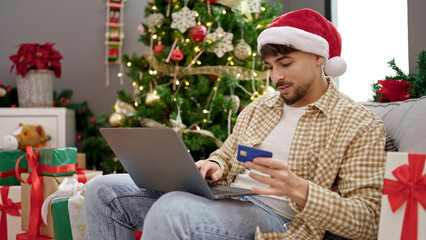 Wall Mural - Young arab man decorating christmas tree at home