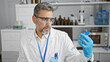 © Krakenimages.com - Attractive young hispanic man, grey-haired chemist, concentrating on measuring liquid in test tube at indoor science lab.