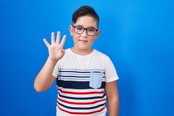 Canvas Print - Young hispanic kid standing over blue background showing and pointing up with fingers number four while smiling confident and happy.