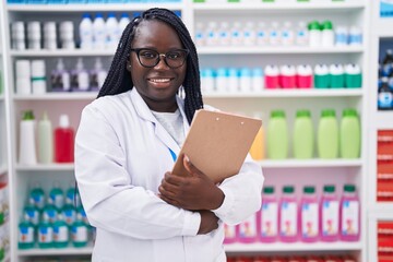 Canvas Print - African american woman pharmacist smiling confident holding clipboard at pharmacy