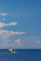 cargo ship nearby Capo Peloro Lighthouse in Punta del Faro on the Strait of Messina, most north eastern promontory of Sicily, Italy