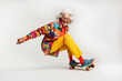 © Ishra - Mature funny older woman with wrinkled face in colorful clothes on skateboard isolated in white background, An energetic happy grandmother on skateboard, playful funky poses of an adult woman skating