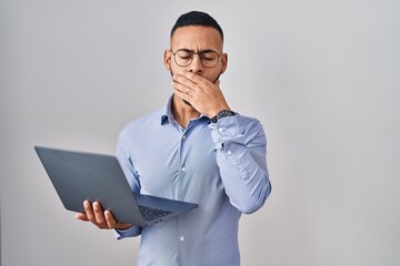 Poster - Young hispanic man working using computer laptop bored yawning tired covering mouth with hand. restless and sleepiness.