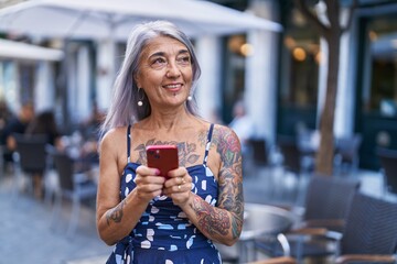 Canvas Print - Middle age grey-haired woman smiling confident using smartphone at street