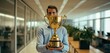 man holding gold trophy in office