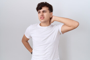 Poster - Young non binary man wearing casual white t shirt suffering of neck ache injury, touching neck with hand, muscular pain