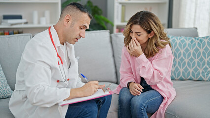 Canvas Print - Man and woman doctor and patient writing medical report doing thumb up gesture at the clinic