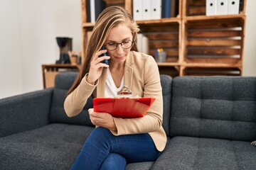 Sticker - Young blonde woman psychologist talking on smartphone reading document at psychology clinic