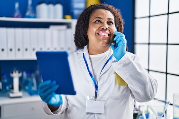 Canvas Print - African american woman scientist talking on smartphone using touchpad at laboratory