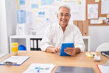 Wall Mural - Middle age grey-haired man business worker smiling confident using touchpad at office