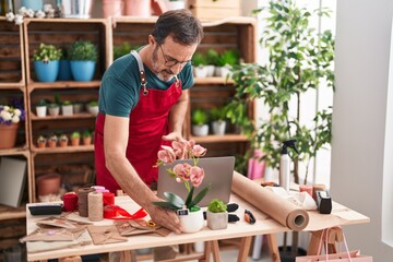 Wall Mural - Middle age man florist using laptop holding plant at florist