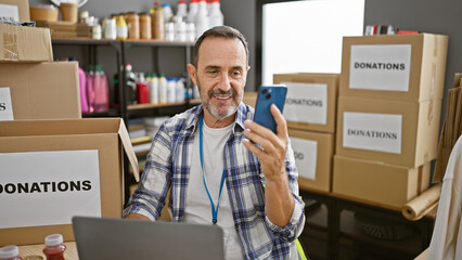 Sticker - Middle age man with grey hair volunteer having video call by smartphone at charity center