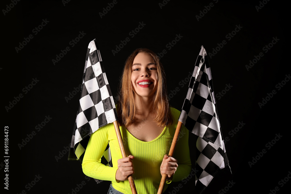Beautiful young woman with racing flags on black background