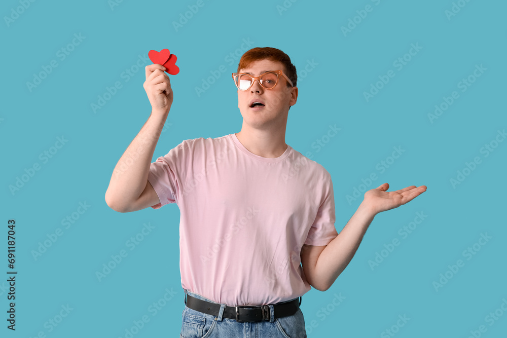 Young man with red paper hearts on blue background