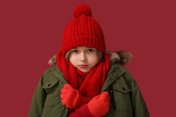 Sticker - Frozen cute little boy in warm winter clothes on red background