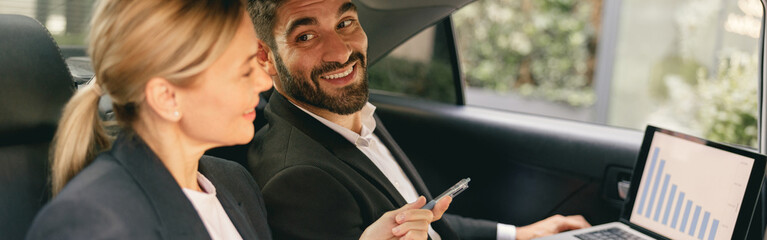 Wall Mural - Business colleagues working on laptop while sitting in car backseats. High quality photo