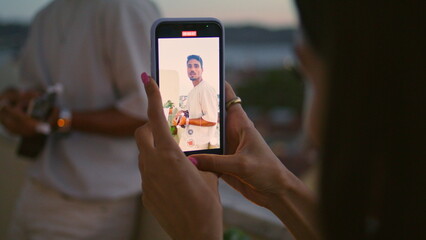 Wall Mural - Woman hands recording video of man evening balcony. Relaxed guy play guitar