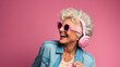 Crazy cool granny, elderly woman with headphones, sunglasses and gray hair, expressive mature and happy smiling grandmother in colorful close-up portrait