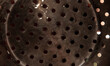 Holes in a metal pressure cooker as an abstract background