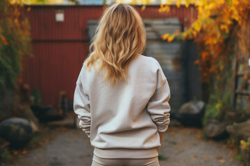 Wall Mural - Fashion and style concept. Woman with white blank sweatshirt portrait. Girl standing back to camera in yellow autumn trees background. Model wearing white blank sweatshirt or sport jumper