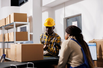 Wall Mural - African american man and woman storehouse coworkers chatting at storage room counter desk. Postal service employees discussing parcel dispatching at post office reception table