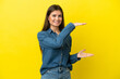 Young caucasian woman isolated on yellow background holding copyspace to insert an ad