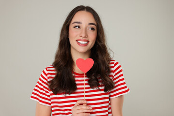 Sticker - Beautiful young woman with paper heart on grey background