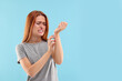 Suffering from allergy. Young woman scratching her arm on light blue background, space for text