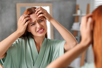 Canvas Print - Suffering from allergy. Young woman checking her face near mirror in bathroom