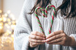 Close up of female hands holding candy canes in the form of heart.