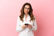 © luismolinero - Middle aged caucasian woman isolated on pink background sending a message with the mobile