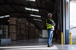 © Halfpoint - Portrait of warehouse worker taking break from work, standing and looking outdoors. Worker in reflective clothes, with copy space.