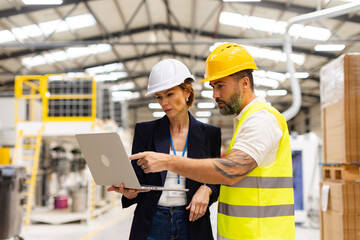 Female manager talking with foreman, checking production plan on notebook. Woman quality controller checking quality of products, talking with technician.