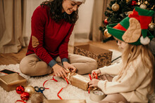 Mom and child wrapping Christmas presents in the living room