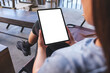 © Farknot Architect - Mockup image of a woman holding digital tablet with blank white desktop screen in cafe