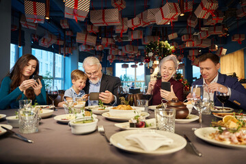 People using mobile phone scrolling online while having Christmas dinner