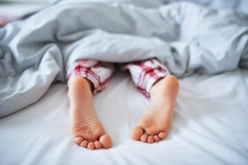 Wall Mural - Little child's feet in bed covered with blanket