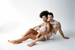 © LIGHTFIELD STUDIOS - appealing sexy multicultural couple in comfy underwear sitting on floor and hugging lovingly