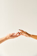 cropped view of multiracial young couple touching hands and fingers of each other on ecru background