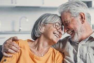 Wall Mural - Happy mature husband and wife sit rest on couch at home hugging and cuddling, show care affection, smiling senior loving couple relax on sofa have fun, enjoy tender romantic family weekend together.