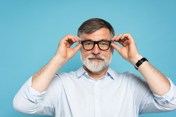 Sticker - Happy caucasian mature man trying new glasses and smiling, standing on blue background