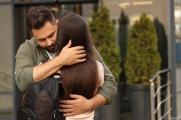 Canvas Print - Long-distance relationship. Young couple with backpack hugging outdoors, space for text